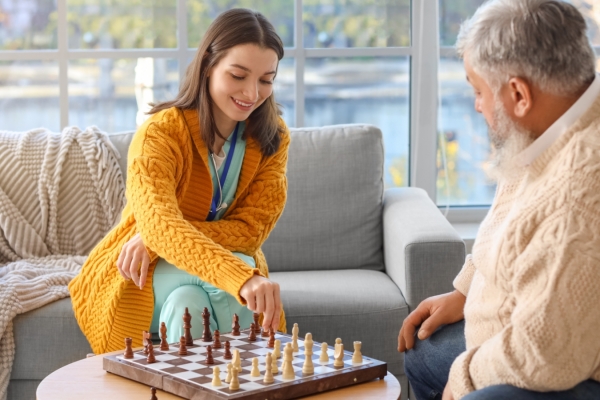 Woman plays chess with older man